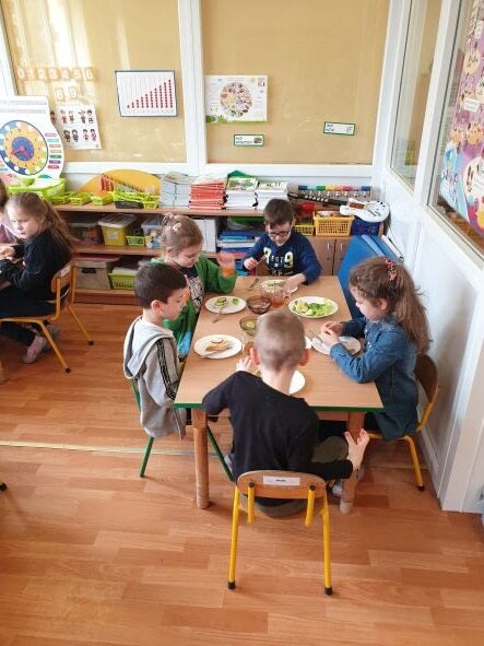 Dzieci siedzą przy stole, przygotowują drugie śniadanie.