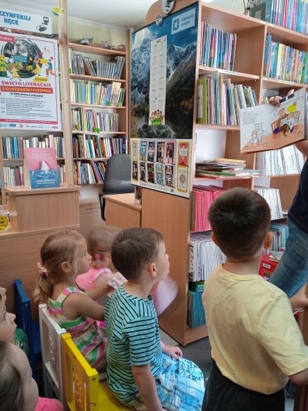 Dzieci słuchają bajki czytanej przez pana bibliotekarza.